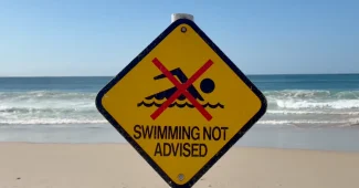 Plage avec parasol et panneau d'information sur les règles de sécurité
