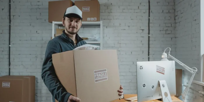 Entrepôt e-commerce avec rangées de colis et boîtes organisés, main d'un employé saisissant un article