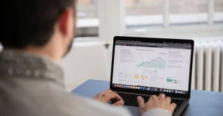 Mains tapant sur un clavier d'ordinateur avec un tableau de bord d'analyse visible à l'écran