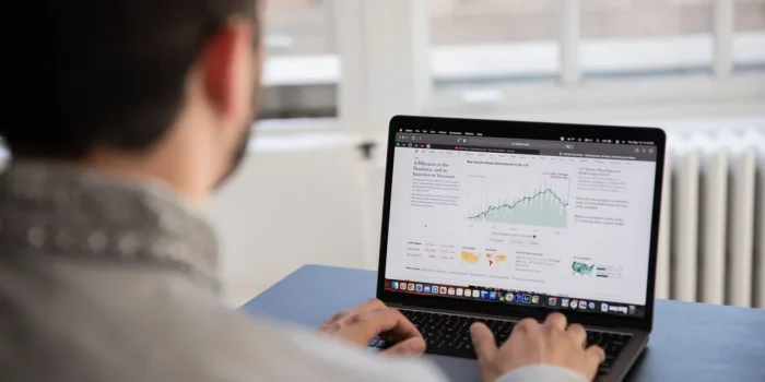 Mains tapant sur un clavier d'ordinateur avec un tableau de bord d'analyse visible à l'écran