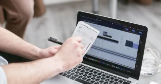 Mains anonymes remplissant un formulaire en ligne sur un ordinateur portable dans un bureau