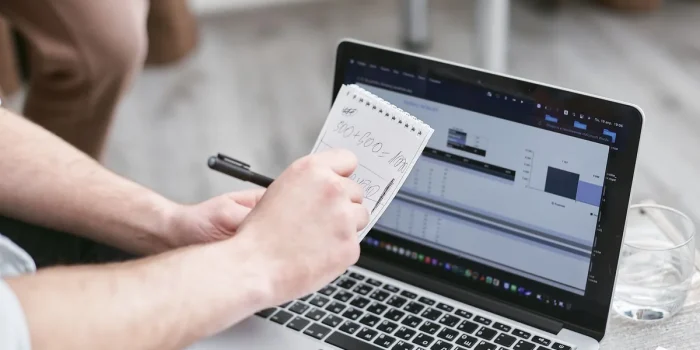 Mains anonymes remplissant un formulaire en ligne sur un ordinateur portable dans un bureau