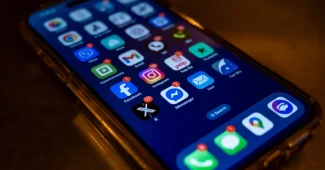 Téléphone affichant un message d'alerte arnaque avec symboles d'avertissement sur un bureau