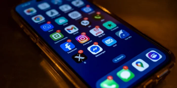 Téléphone affichant un message d'alerte arnaque avec symboles d'avertissement sur un bureau