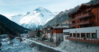 Village alpin enneigé dans les montagnes avec chalets et domaines skiables visibles