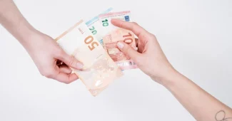 Main tenant un billet en euros avec écran de consultation floue en arrière-plan