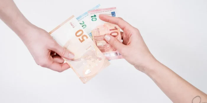 Main tenant un billet en euros avec écran de consultation floue en arrière-plan