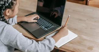 Étudiant en train de relire et corriger un devoir sur son ordinateur portable à un bureau