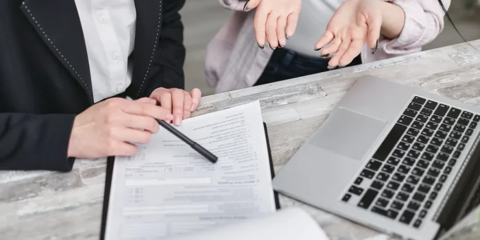 Mains tenant un contrat d'assurance ouvert à côté d'une valise et d'une liste de vérification