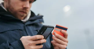 Main tenant une main scrollant sur un téléphone affichant des évaluations en étoiles et avis clients