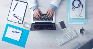 Fournitures scolaires et ordinateur montrant une page administrative floue, symbolisant une aide administrative