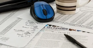 Bureau avec registre financier, dossiers anonymes et main en silhouette prenant des notes