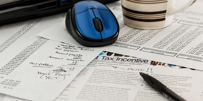 Bureau avec registre financier, dossiers anonymes et main en silhouette prenant des notes