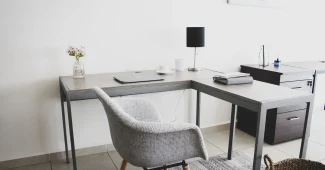 Main anonyme avec carnet et smartphone sur un bureau avec ordinateur portable en lumière naturelle