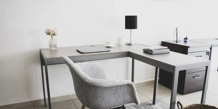 Main anonyme avec carnet et smartphone sur un bureau avec ordinateur portable en lumière naturelle
