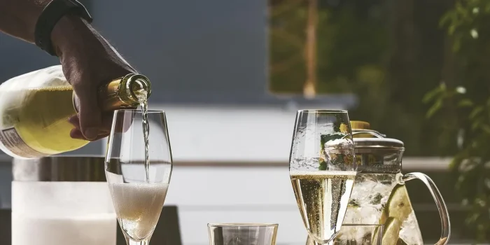Mains anonymes échangeant une gourde inox et un tote bag recyclé sur une table de bureau