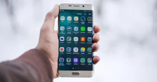 Main tenant un smartphone affichant une interface de messagerie riche avec boutons et carrousel