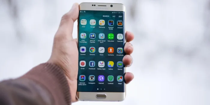 Main tenant un smartphone affichant une interface de messagerie riche avec boutons et carrousel