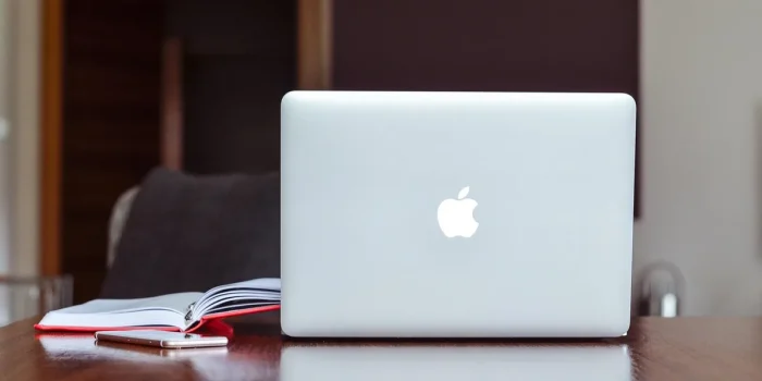 Bureau en journée avec ordinateur, planning et carnet, mains prenant des notes