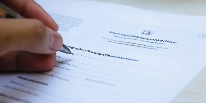 Main d'une personne tenant un smartphone et un bloc-notes, avec des documents sur un bureau, pour documenter une preuve