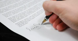 Main posée sur des documents officiels avec un stylo, symbolisant une décision importante concernant l'héritage