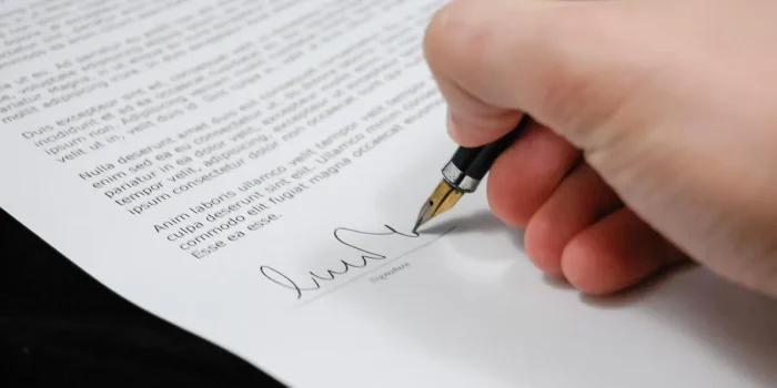 Main posée sur des documents officiels avec un stylo, symbolisant une décision importante concernant l'héritage