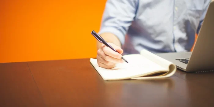 Mains triant une liste de contacts sur un bureau avec un ordinateur portable et documents