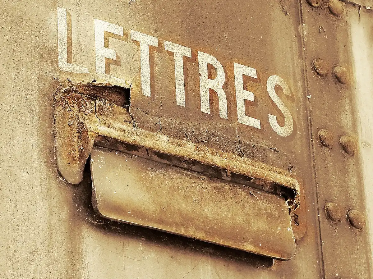 Main tenant une lettre de réclamation avec enveloppe près d'un ordinateur