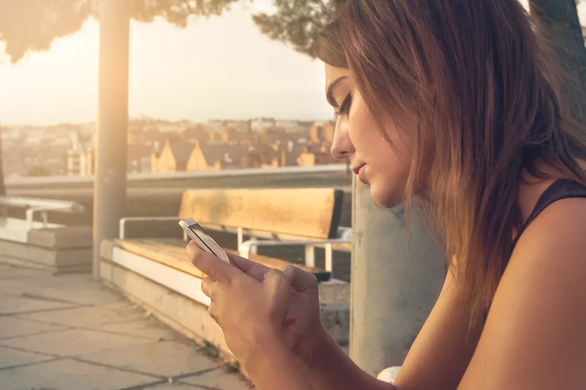 Main scannant un QR code dans un catalogue avec un smartphone