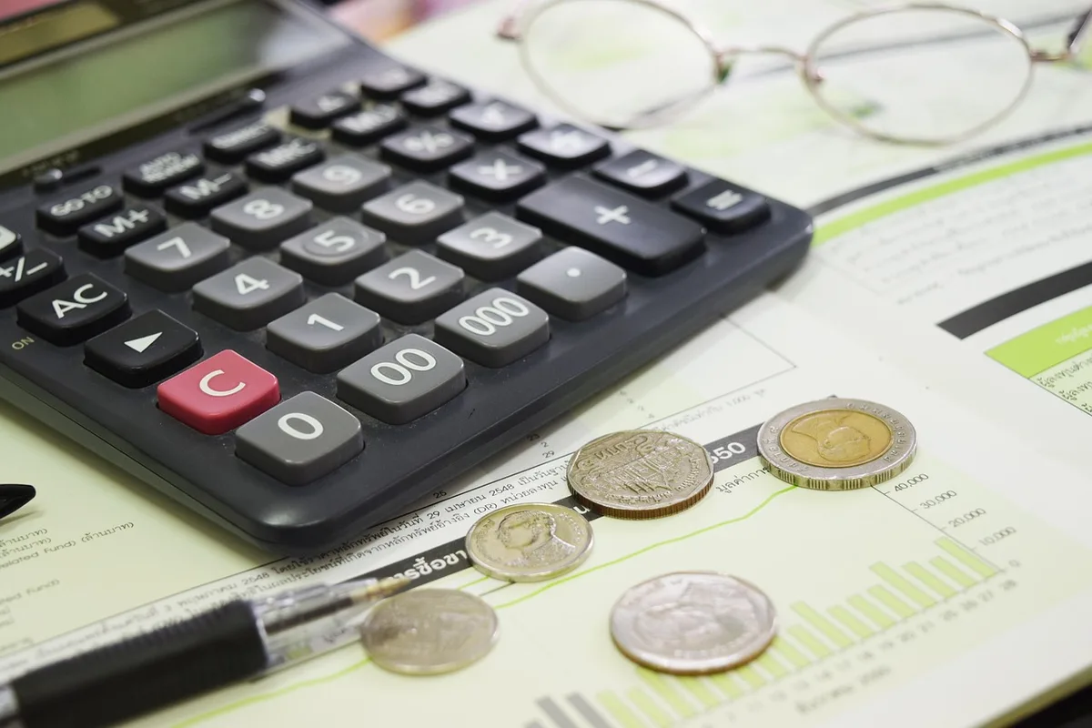 Personne réorganisant un budget mensuel avec calculatrice et relevés