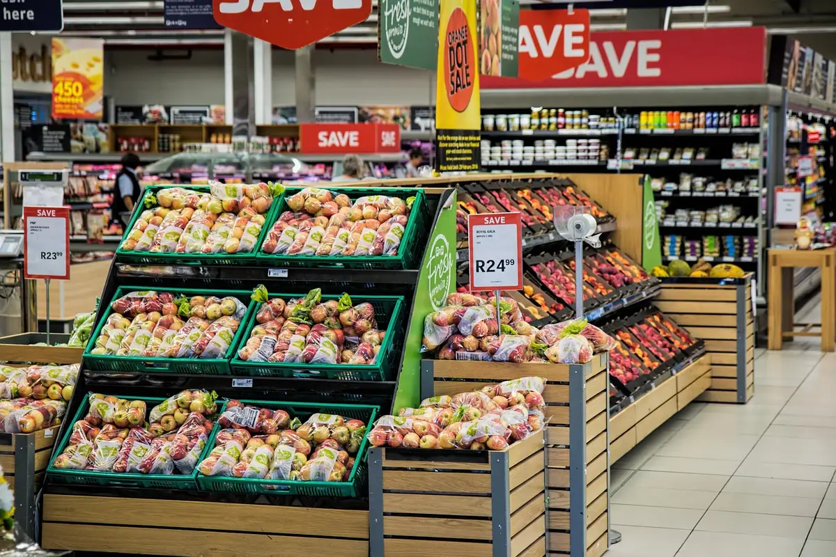 Caddie de courses dans un supermarché près des rayons de fruits et légumes