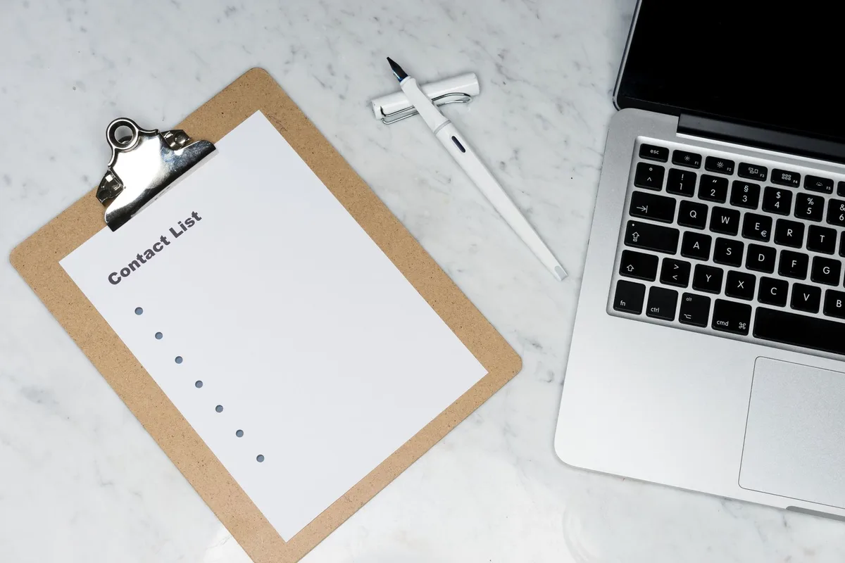Main annotant une checklist de qualification des prospects sur un bureau ensoleillé