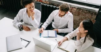 Équipe discutant d'un tableau CRM sur un ordinateur portable dans un bureau en plein jour