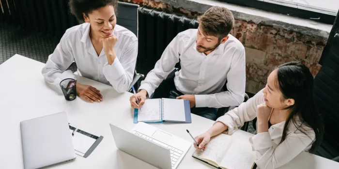 Équipe discutant d'un tableau CRM sur un ordinateur portable dans un bureau en plein jour
