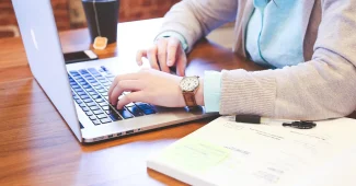 Mains devant un ordinateur et graphiques sur un bureau en plein jour
