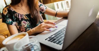 Deux mains féminines tenant un carnet sur une table de coworking en pleine journée