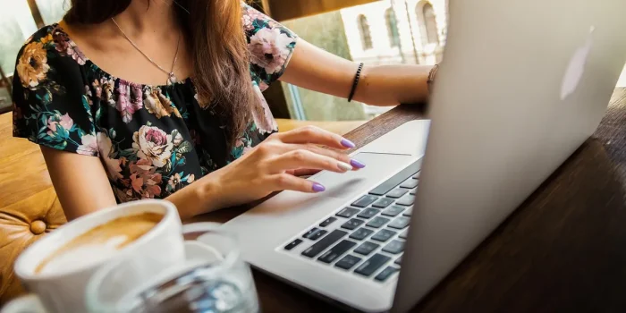 Deux mains féminines tenant un carnet sur une table de coworking en pleine journée