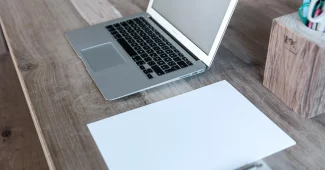 Bureau lumineux avec ordinateur portable, carnet et mains en train de taper