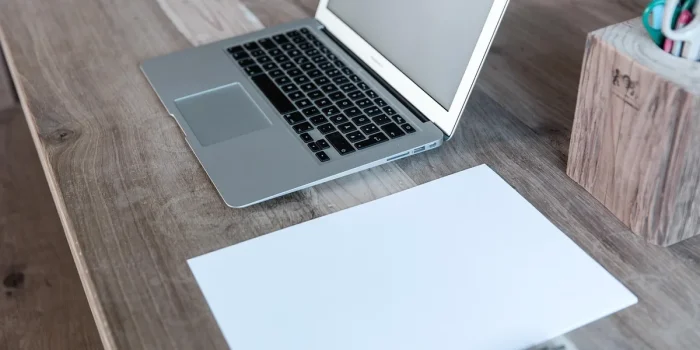 Bureau lumineux avec ordinateur portable, carnet et mains en train de taper